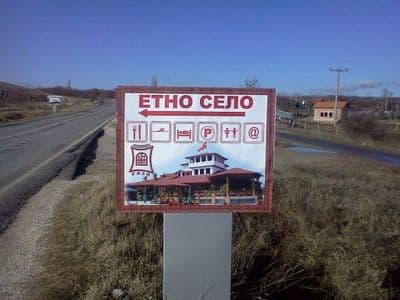 Табла покрај пат за етно село со фотографија и икони